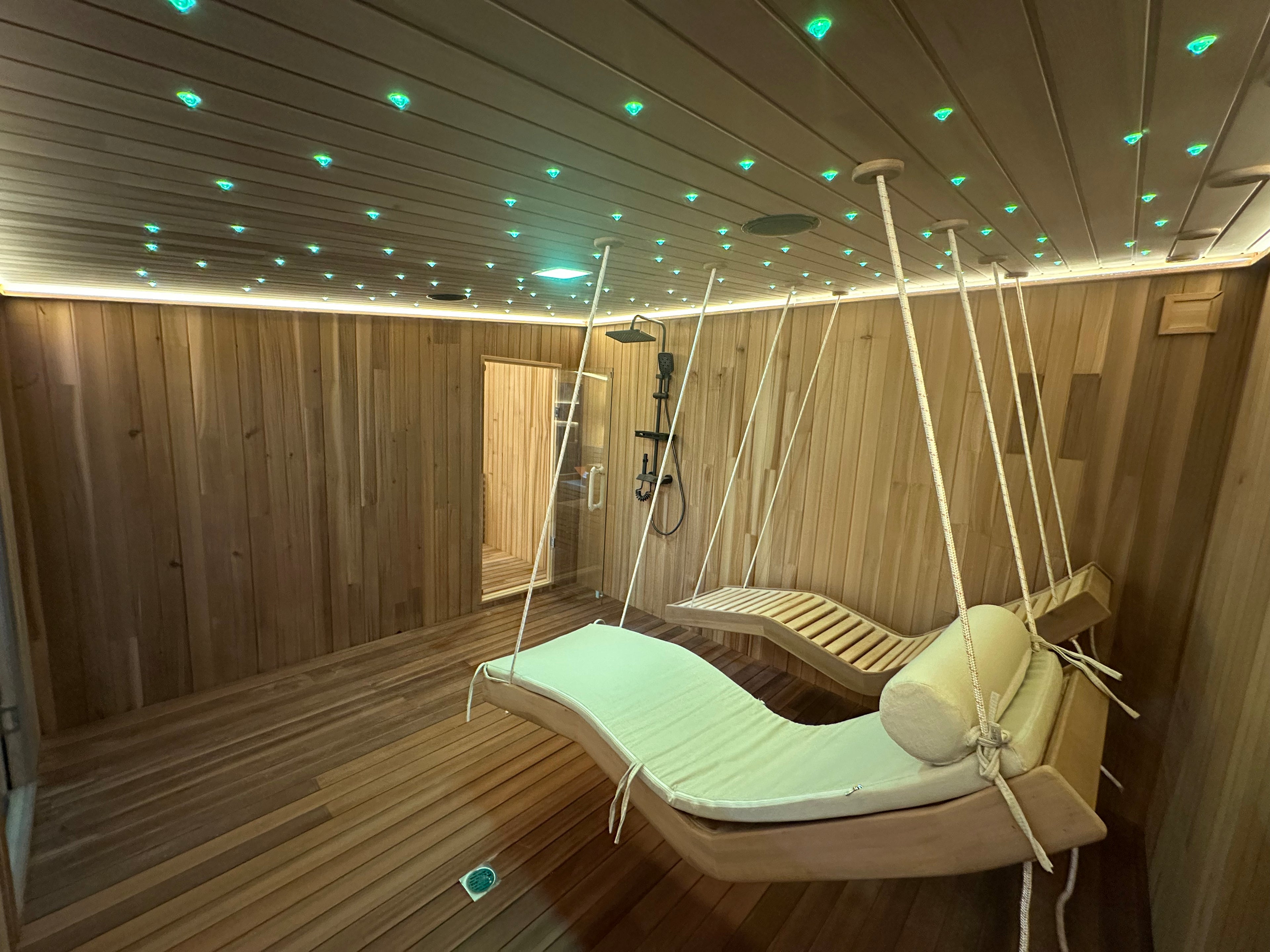 Large - sized sauna, suitable for 4 - 6 people, with bathroom facilities inside and a customized hanging chair.